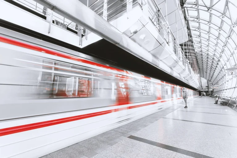 Een man staat op de trein naar zijn werk te wachten, waar hij TriFact365 gebruikt voor een optimale samenwerking.