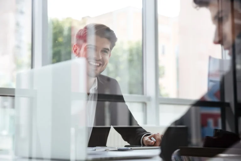 Jongen kijkt blij naar zijn collega, terwijl zijn collega naar een computerscherm kijkt en bezig lijkt te zijn met Future Proof Accounting.