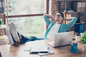 Man zit te ontspannen achter zijn computer, omdat veel van zijn taken worden overgenomen door Robotic Accounting.