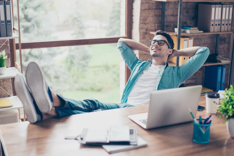 Man zit te ontspannen achter zijn computer, omdat veel van zijn taken worden overgenomen door Robotic Accounting.