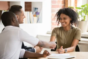 Een vrouw geeft een man lachend een hand, waarvan ze de contactgegevens makkelijk in een CRM vastlegt.