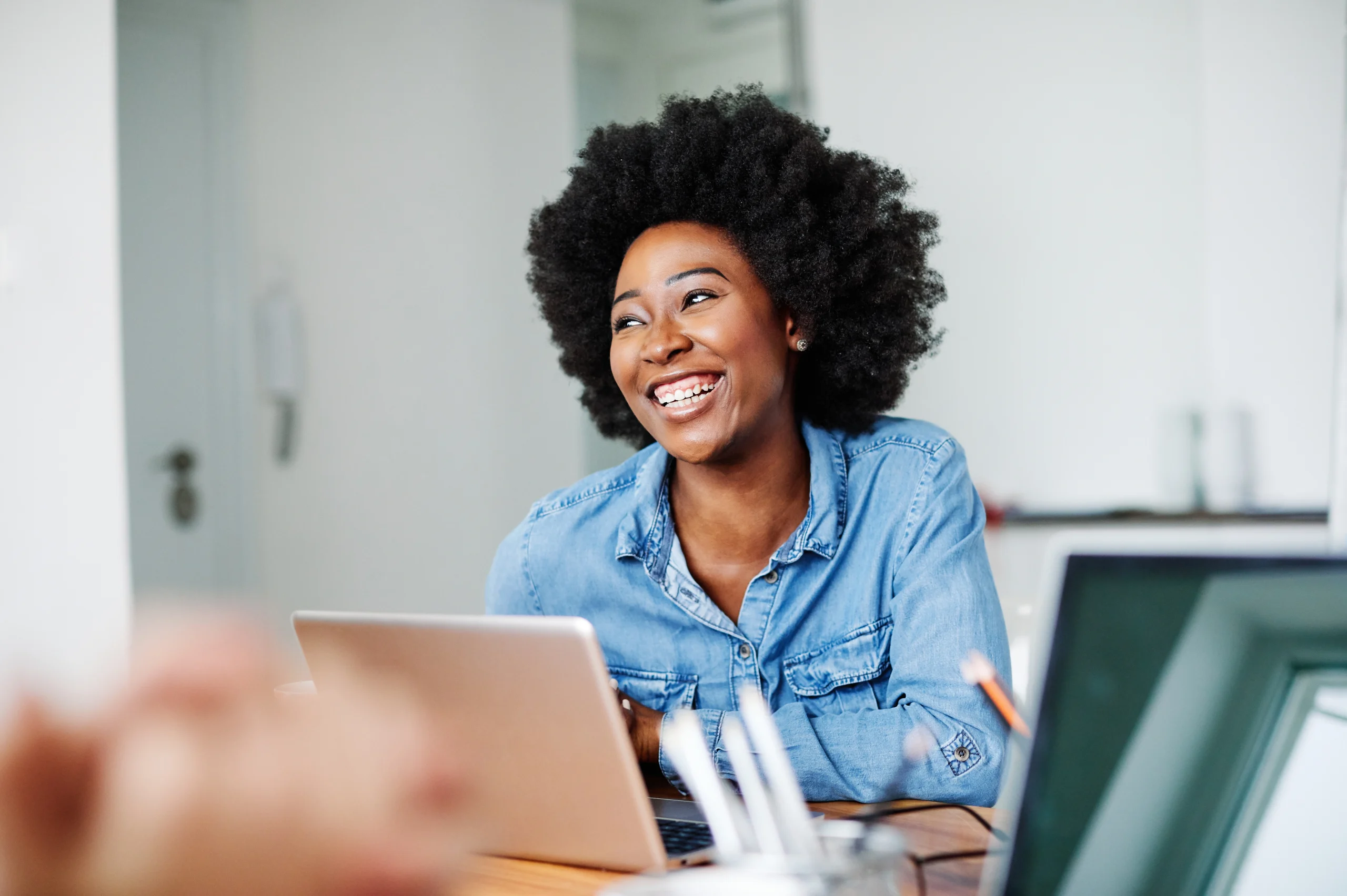 A woman sits at her computer and smiles because of the efficiency of automatic invoice processing.