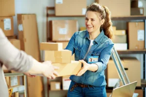 Een vrouw neemt lachend een pakket aan waarmee een retour wordt aangeduid die in verband staat met een creditfactuur.