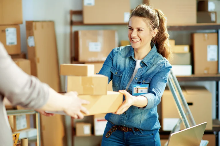 Een vrouw neemt lachend een pakket aan waarmee een retour wordt aangeduid die in verband staat met een creditfactuur.