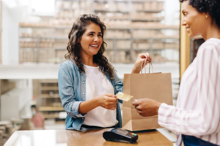 Een ondernemende vrouw geeft lachend een bankpas terug, voordat ze omzetbelasting aangifte doet.