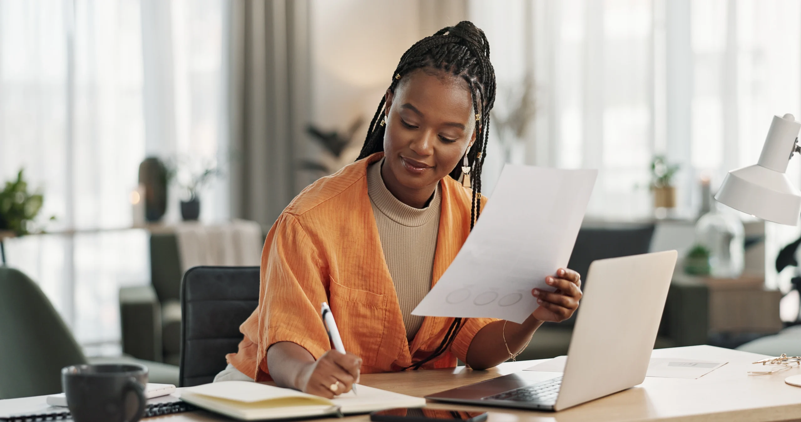 A woman laughingly signs an invoice and is in the process of authorising invoices.