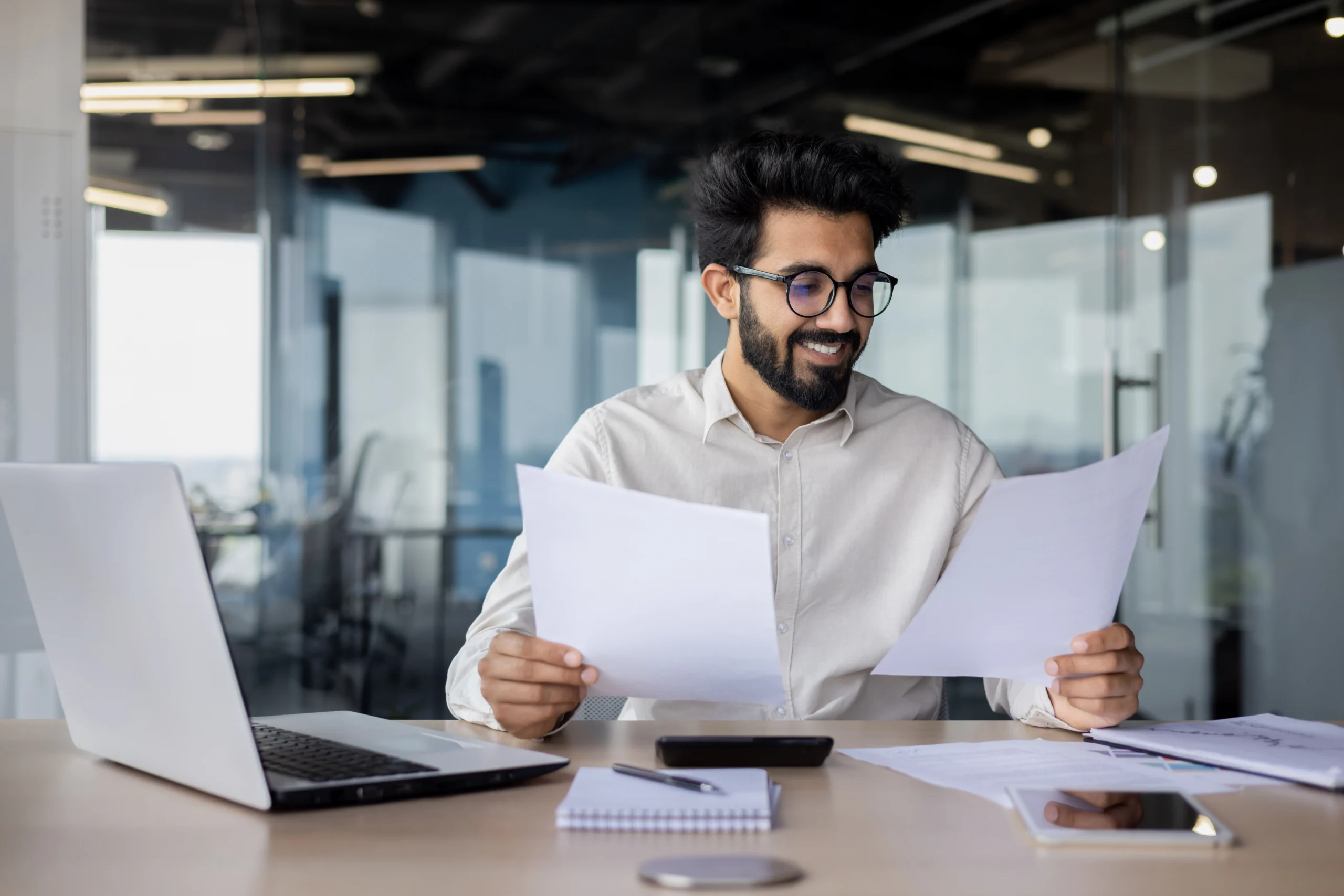 Man looks at papers smiling as he is busy making invoices.