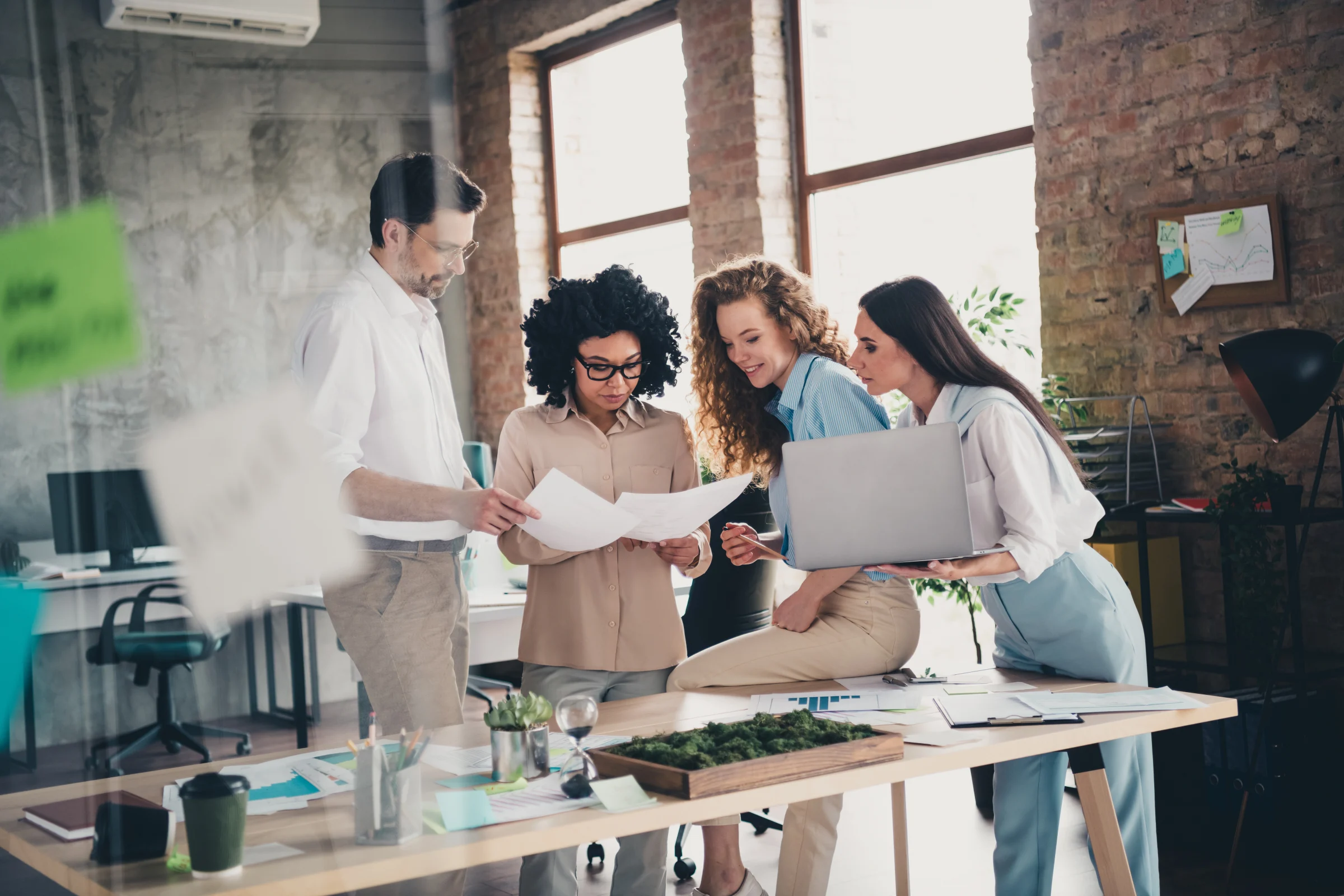 Collega's die achter een bureau staan samen te werken en gebruik te maken van Google Workspace.