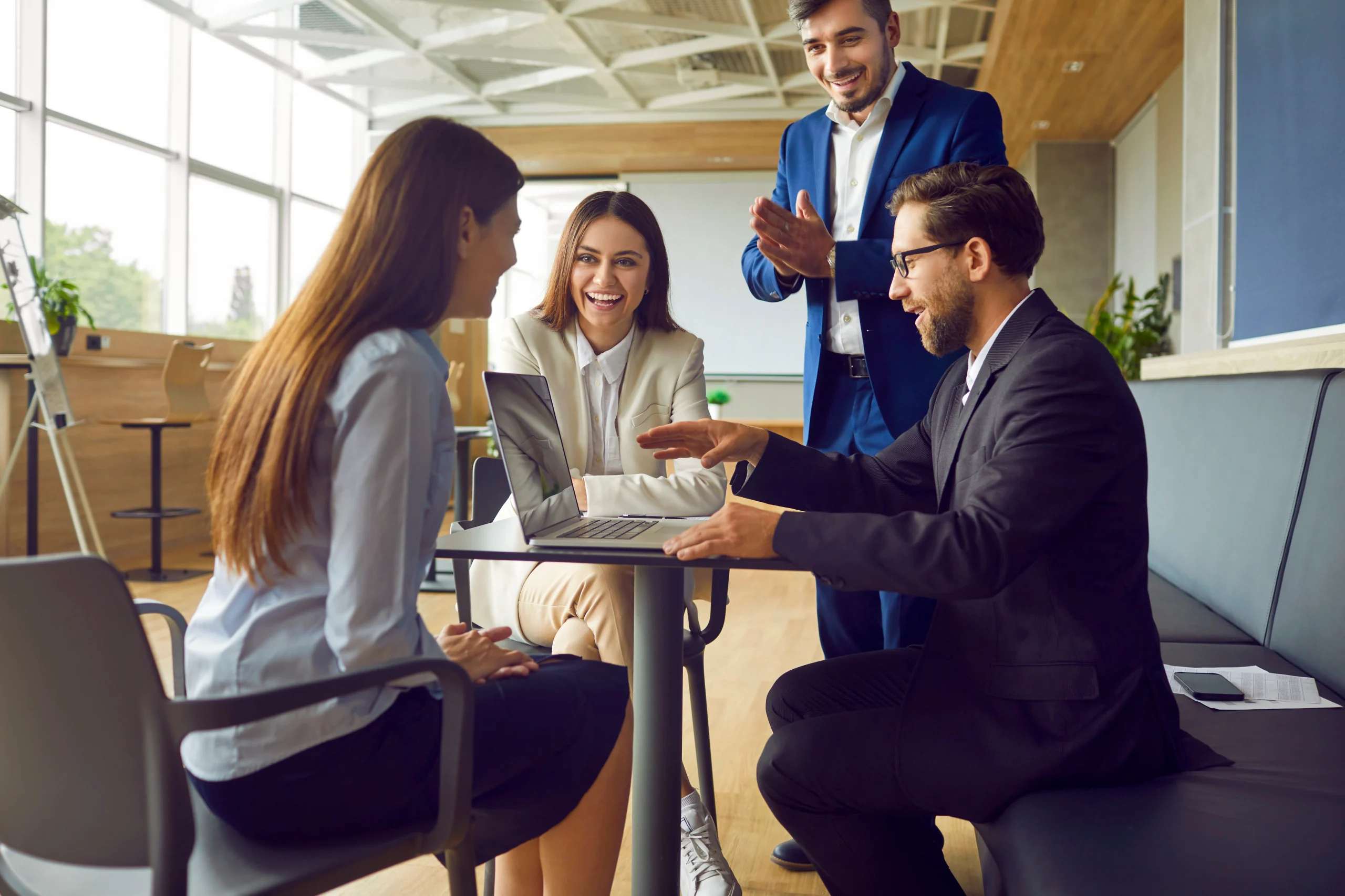 Parece que un grupo de compañeros trabaja junto a un ordenador que ejecuta el software Sharepoint.