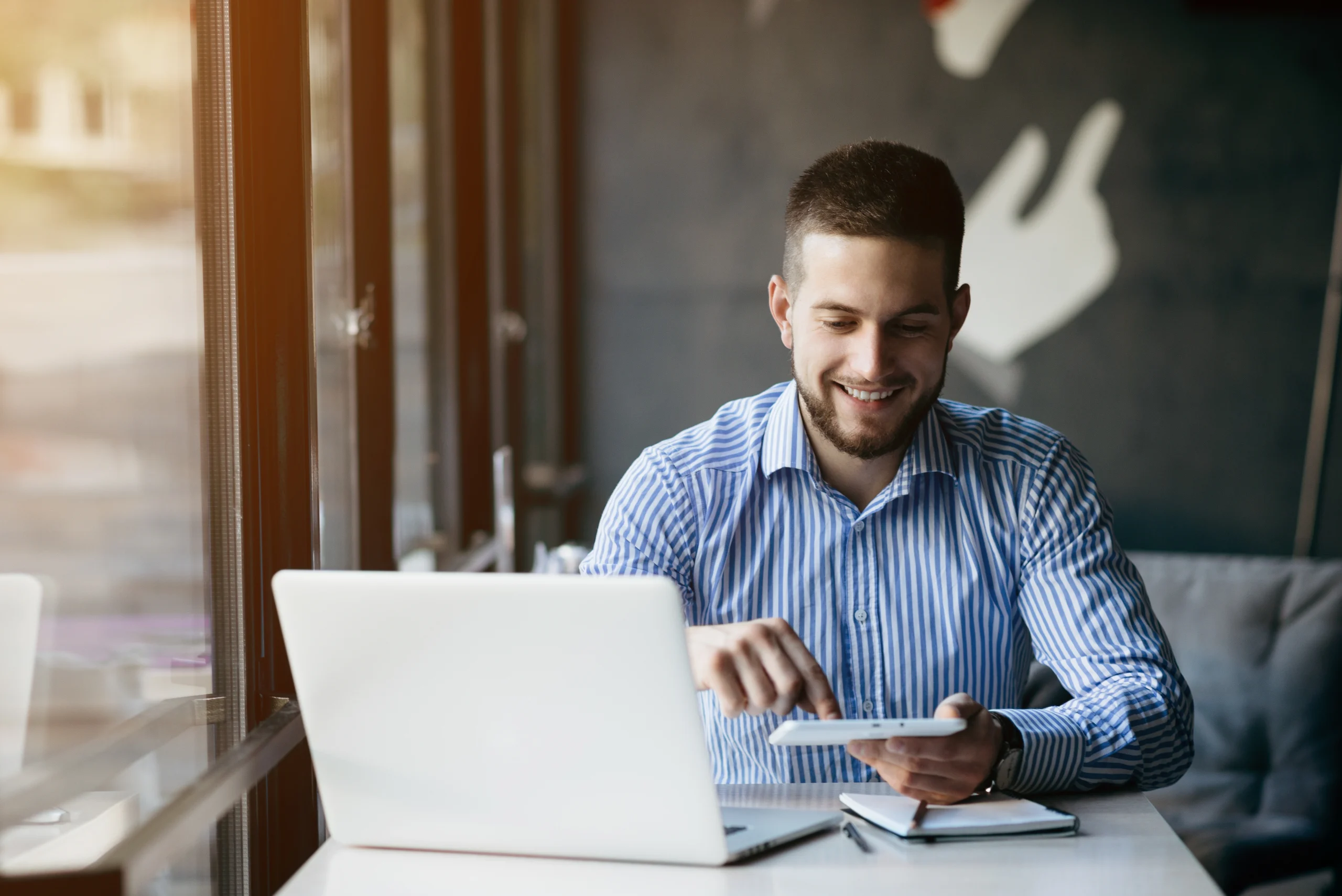 A man laughingly works on his laptop with software that has rule recognition.