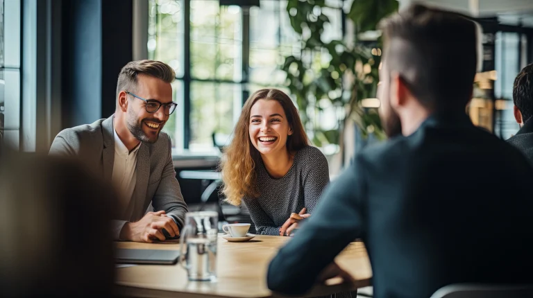 Een man een een vrouw van afdeling inkoop van een bedrijf, zitten lachend aan tafel.