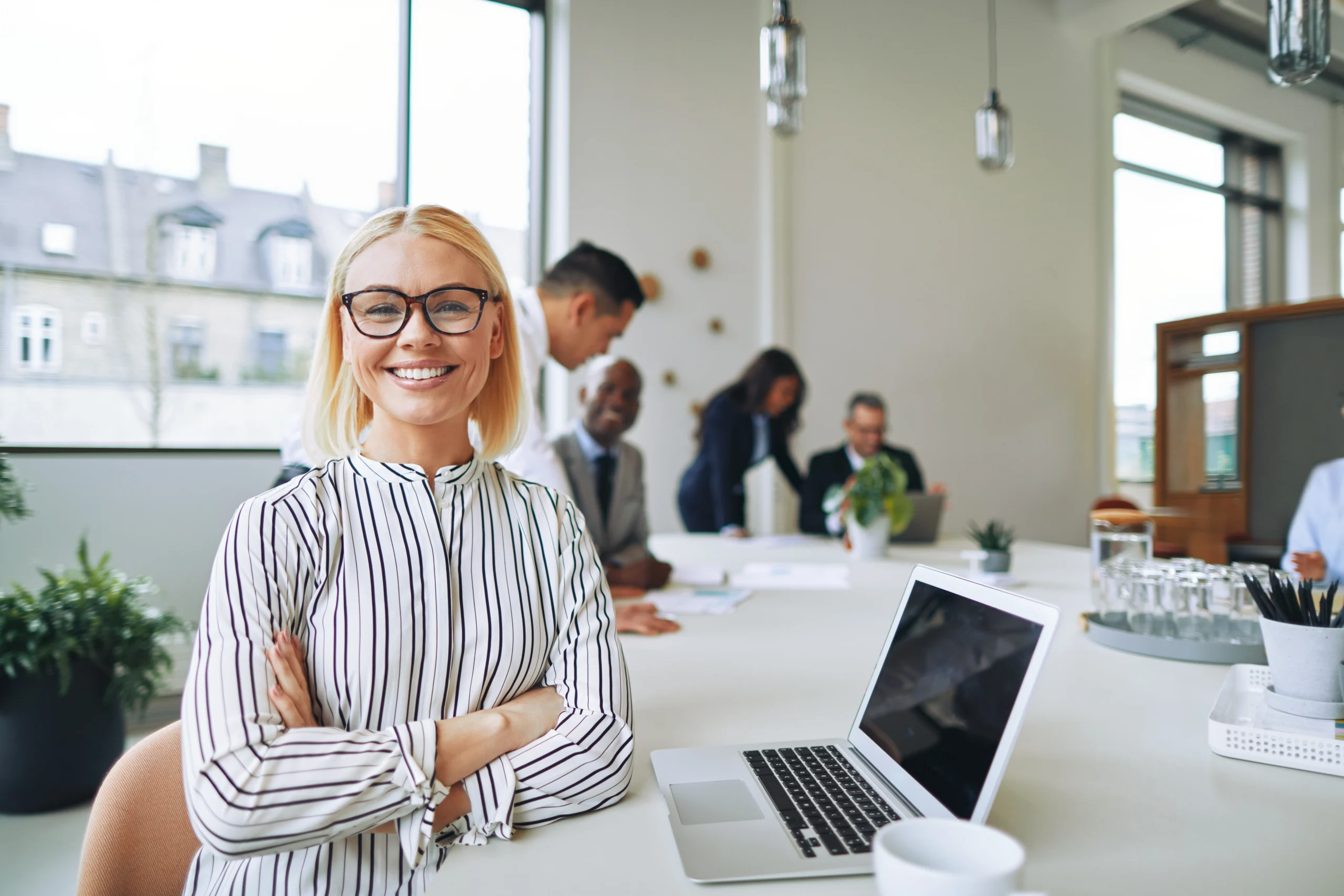 Une femme travaillant dans le service des ressources humaines d'une entreprise regarde la caméra en souriant.