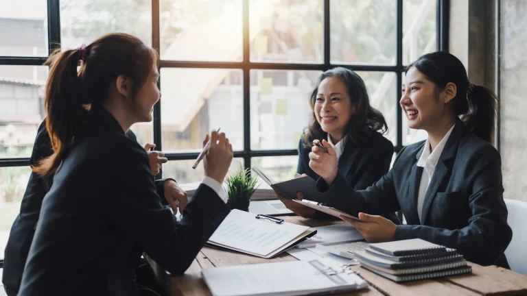 Een aantal vrouwen zitten samen aan tafel om de Winst- en Verliesrekening door te nemen.