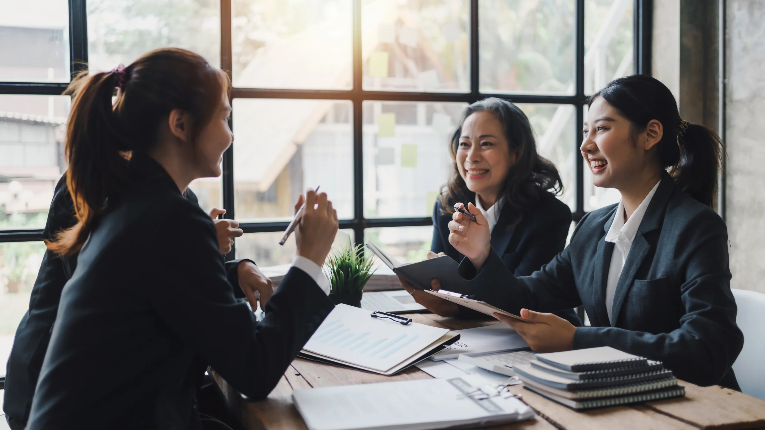 Een aantal vrouwen zitten samen aan tafel om de Winst- en Verliesrekening door te nemen.