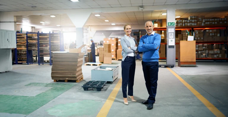 Een man en een vrouw staan samen in een logistieke opslagplaats om te overleggen over Vlottende Activa.