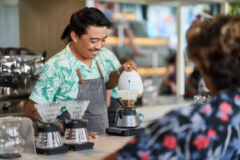 Een man schenkt lachend koffie in terwijl hij nadenkt over de KOR en One Stop Shop.