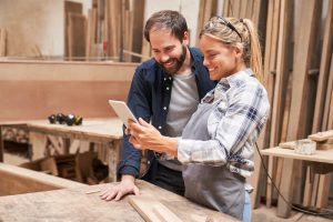 Man and woman look at tablet at woodworking company
